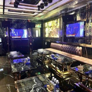 Phòng hát ốp đá vân đen tại Karaoke Level, sofa nỉ màu be, bàn khung mạ vàng, hai màn hình