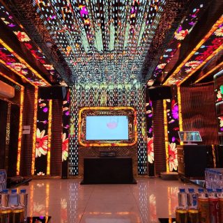 Phòng hát Karaoke Tiptop với tường và trần LED họa tiết hoa rực rỡ, màn hình viền vàng, loa treo và sàn gạch bóng