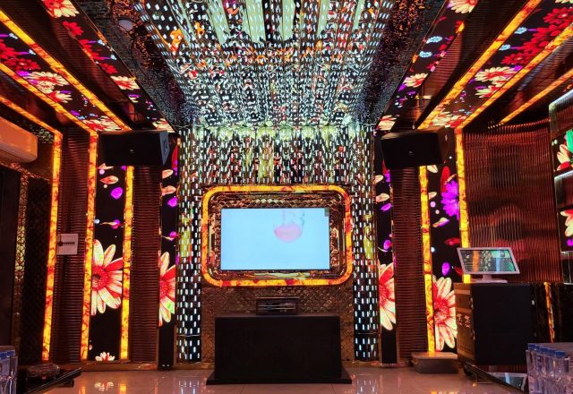 Phòng hát Karaoke Tiptop với tường và trần LED họa tiết hoa rực rỡ, màn hình viền vàng, loa treo và sàn gạch bóng
