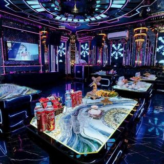 Phòng hát Karaoke Tiptop tông tím xanh, bàn kính vân đá bày ly và trái cây, sofa da tối màu