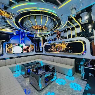 Phòng hát Karaoke Thượng Hải KTV tông trắng xanh, sofa dài chữ L, bàn inox đen bóng, màn hình và đèn LED trên trần