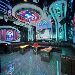 Phòng karaoke tông tối tại S KTV Club, đèn LED xanh ngọc, sofa da đen quây góc và màn hình tivi