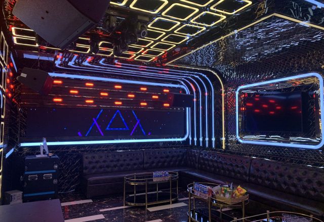 Phòng hát tông tối ở Karaoke Level, trần đèn LED vuông, sofa da đen, xe đẩy đồ uống mạ vàng
