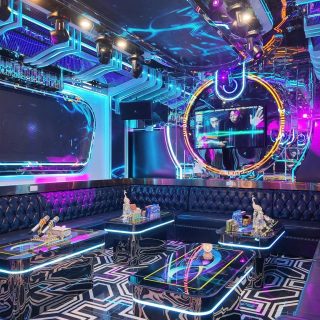 Phòng hát tại Karaoke Royal 97 Cầu Giấy với ghế sofa da đen, bàn viền đèn LED, màn hình và đèn neon xanh tím