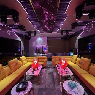 Phòng hát rộng tại Karaoke Royal 97 Cầu Giấy với sofa da vàng, bàn mặt đá, đèn chiếu trần và hai màn hình hai bên