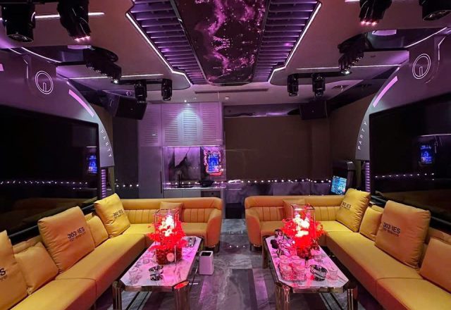 Phòng hát rộng tại Karaoke Royal 97 Cầu Giấy với sofa da vàng, bàn mặt đá, đèn chiếu trần và hai màn hình hai bên