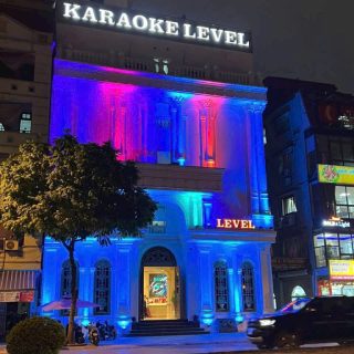 Mặt tiền toà nhà Karaoke Level buổi tối, biển hiệu chữ nổi phát sáng, đèn xanh tím chiếu tường
